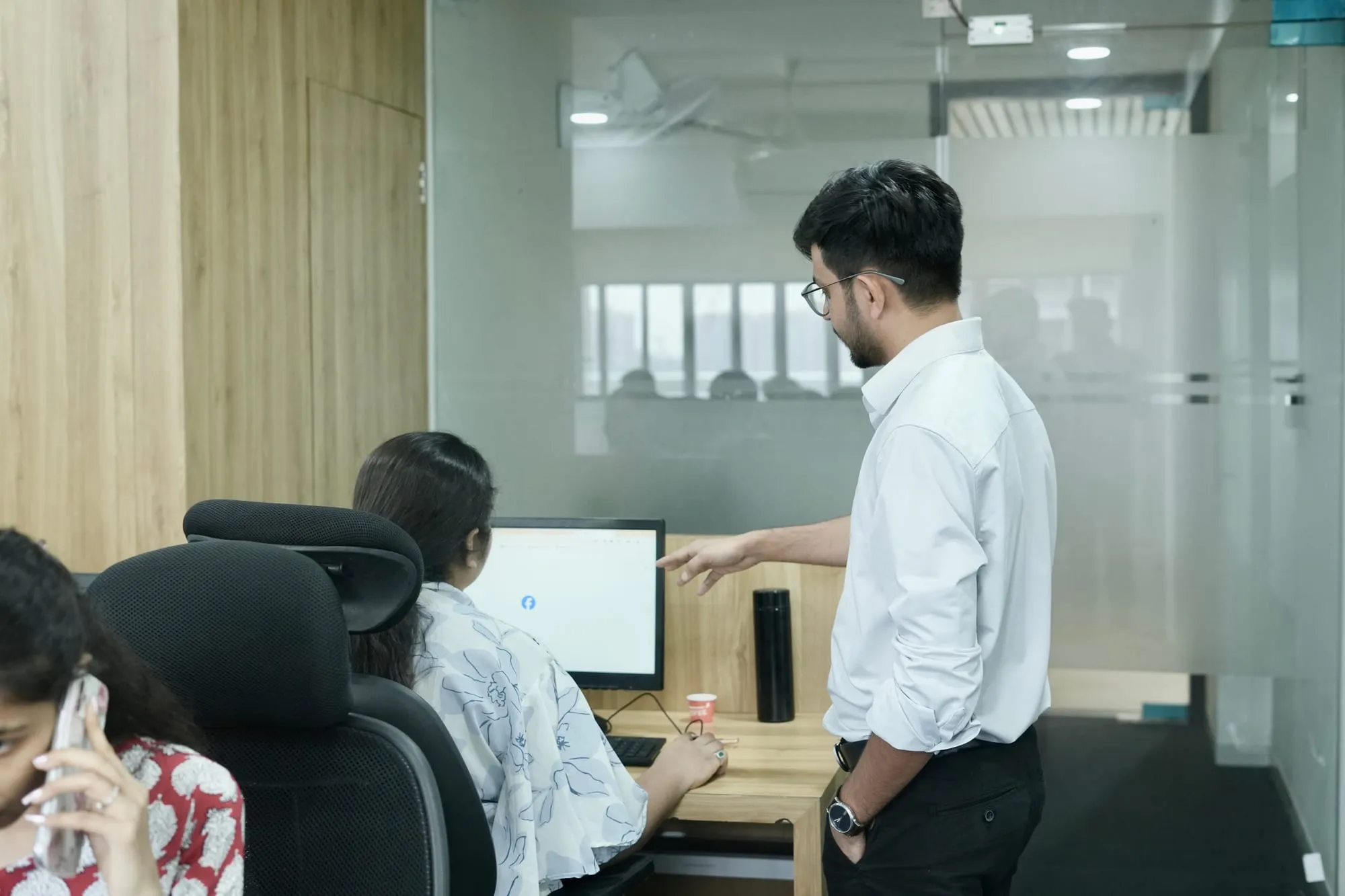 Mukesh Chaudhary guiding a Bizyocon team member at her workstation