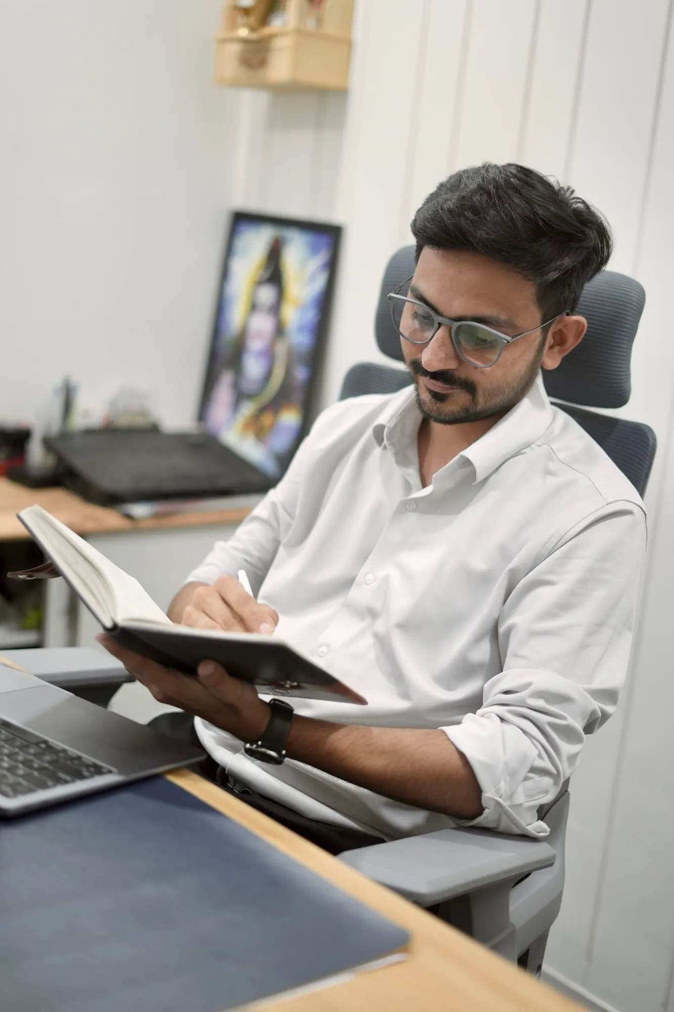 Mukesh Chaudhary planning a marketing strategy Mukesh Chaudhary writing notes in a notebook at his office desk