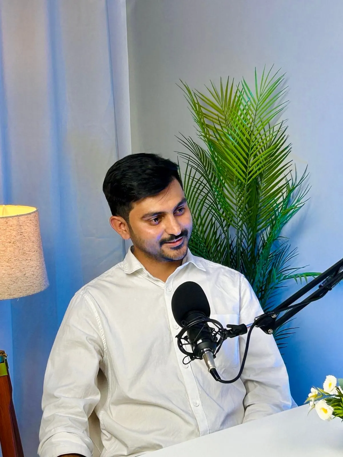 Mukesh Chaudhary speaking into a podcast microphone